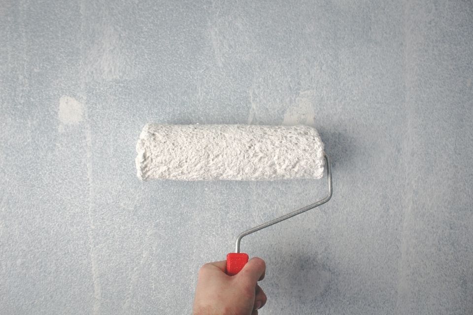 Paint roller painting white wall or primer